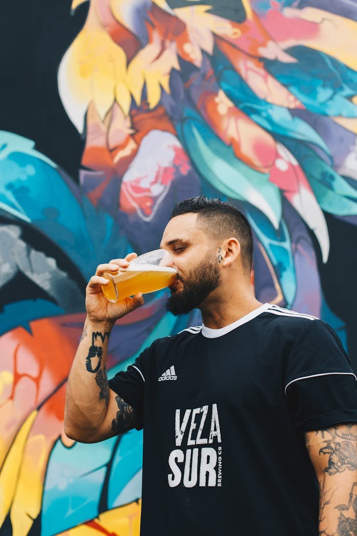 Man drinking craft beer against a vibrant graffiti backdrop. Urban lifestyle vibe.
