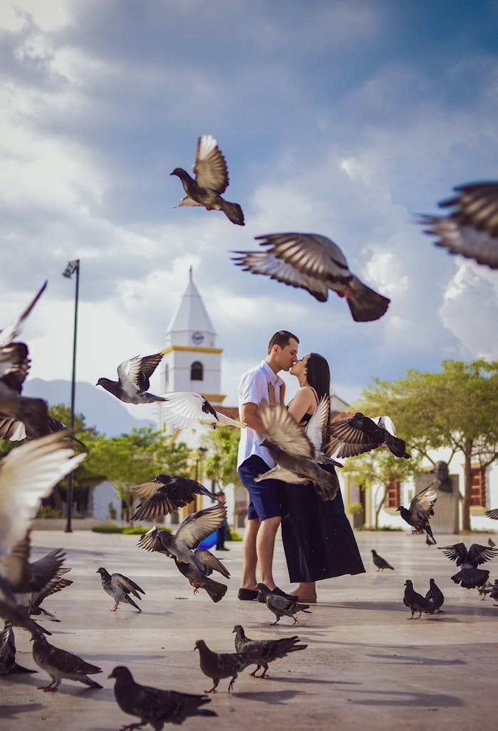 A romantic couple kissing amidst flying pigeons in Valledupar, Colombia.